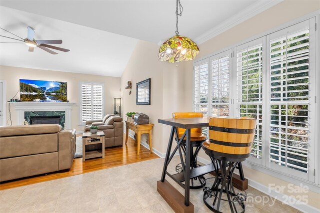 dining area with a high end fireplace, vaulted ceiling, ceiling fan, and baseboards