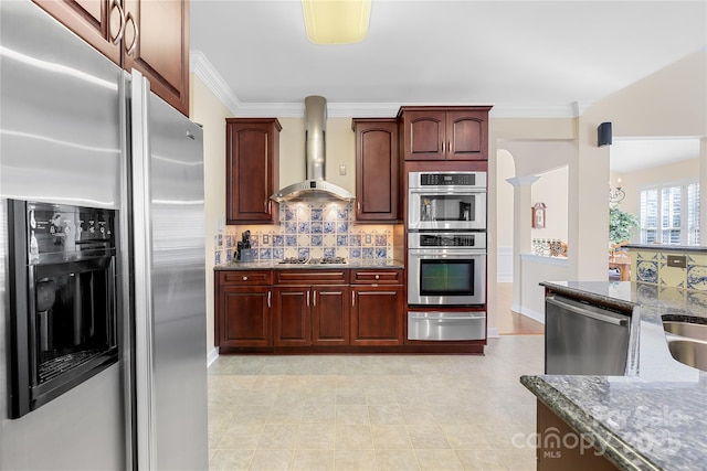 kitchen with stone counters, a warming drawer, appliances with stainless steel finishes, ornamental molding, and wall chimney range hood