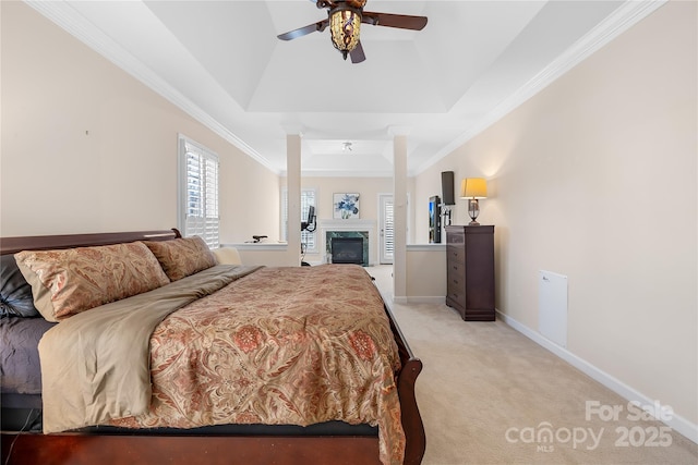 bedroom with a tray ceiling, crown molding, light colored carpet, a glass covered fireplace, and baseboards