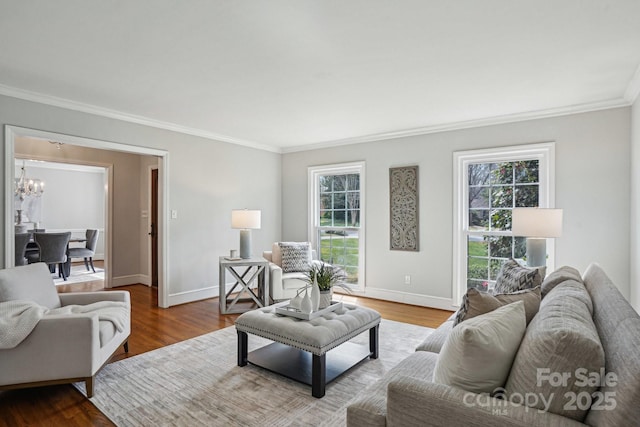 living room with baseboards, ornamental molding, wood finished floors, and a notable chandelier