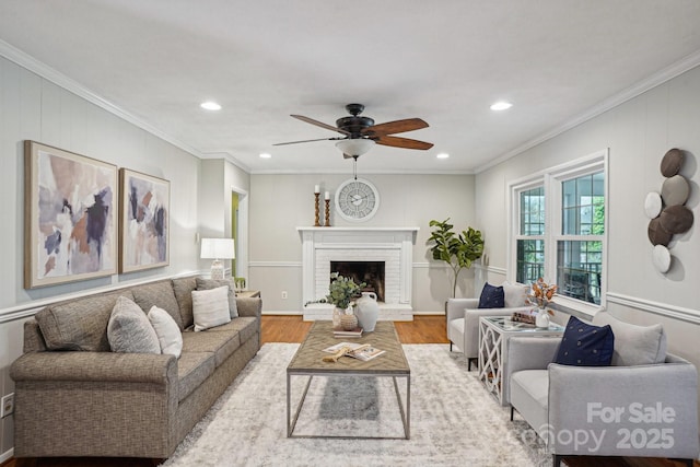 living area featuring ornamental molding, a fireplace, wood finished floors, and recessed lighting