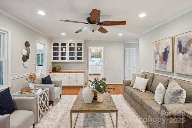 living room with light wood-style flooring, ornamental molding, a ceiling fan, and recessed lighting