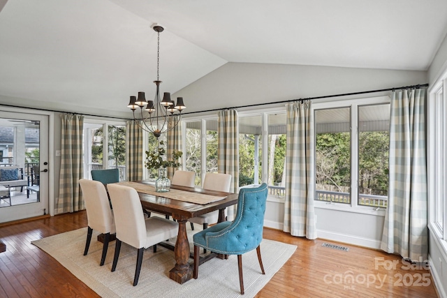 dining area featuring lofted ceiling, a notable chandelier, visible vents, baseboards, and light wood-style floors