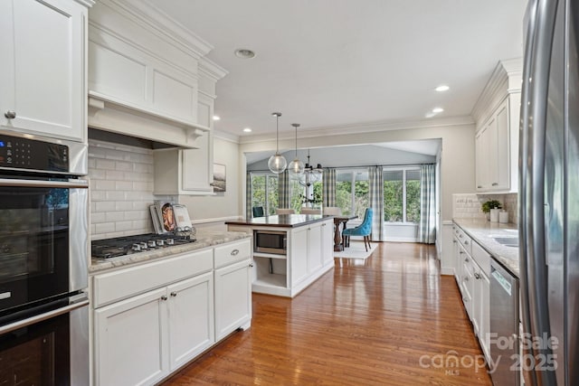 kitchen featuring appliances with stainless steel finishes, light wood-type flooring, white cabinets, and ornamental molding