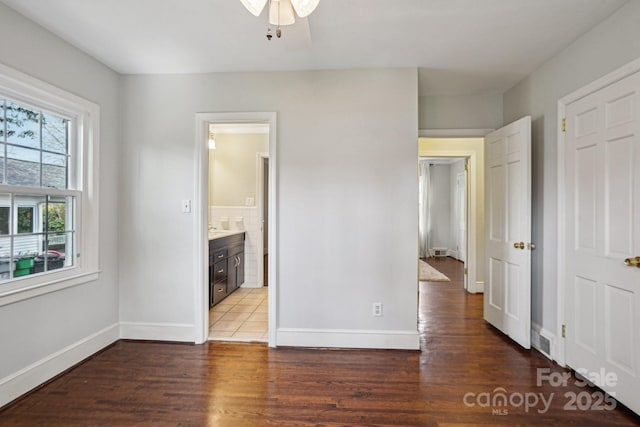 unfurnished bedroom featuring visible vents, baseboards, wood finished floors, ensuite bathroom, and a closet