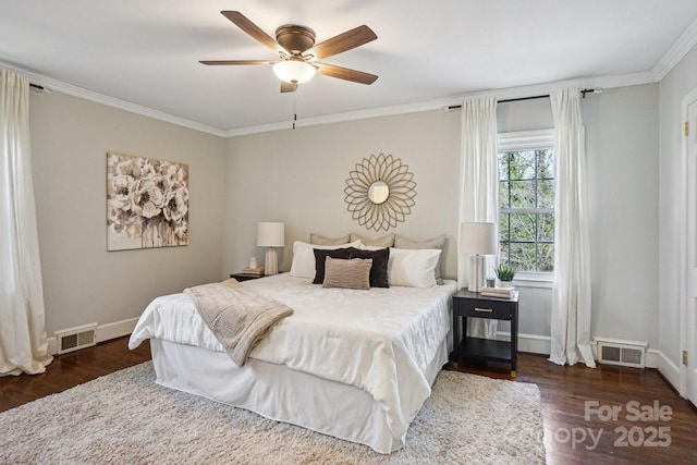 bedroom with baseboards, wood finished floors, visible vents, and crown molding