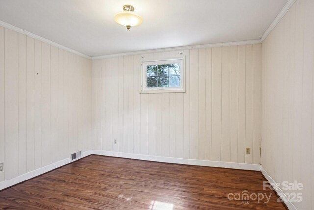 unfurnished room featuring baseboards, visible vents, ornamental molding, and dark wood finished floors