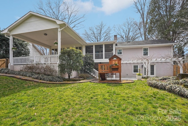 rear view of house featuring a sunroom, a chimney, stairway, and a lawn