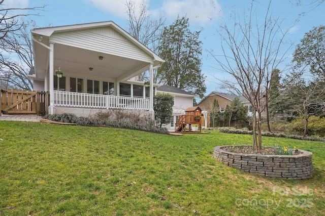 rear view of property featuring a yard, a playground, fence, and a sunroom