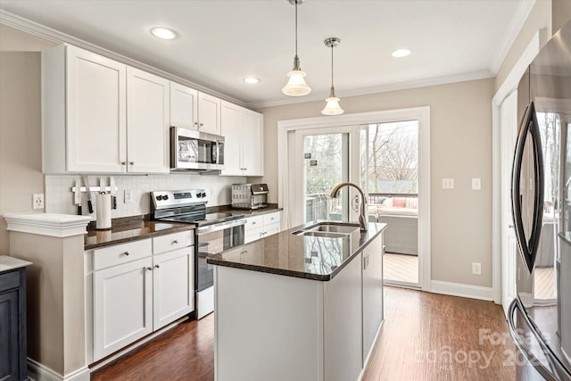 kitchen with a sink, white cabinets, appliances with stainless steel finishes, an island with sink, and pendant lighting