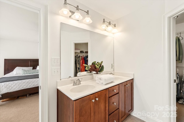 ensuite bathroom featuring ensuite bathroom, double vanity, a sink, and a walk in closet