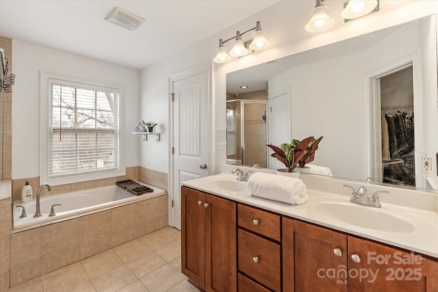 bathroom with double vanity, a stall shower, tile patterned flooring, a walk in closet, and a sink