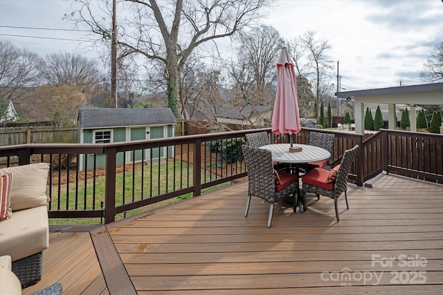 wooden terrace featuring a fenced backyard, an outdoor structure, a yard, a shed, and outdoor dining space