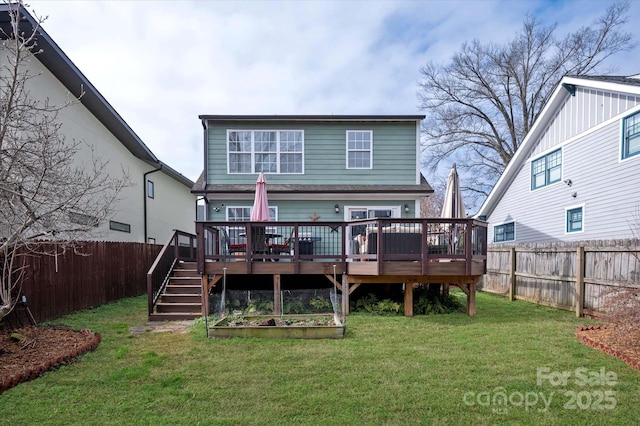 rear view of property featuring a vegetable garden, a fenced backyard, a lawn, and a wooden deck