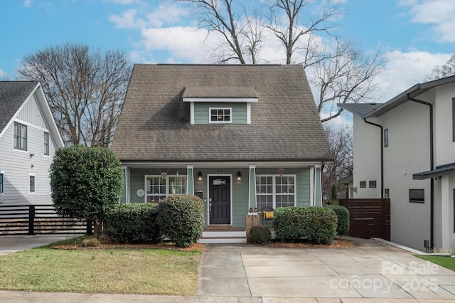 view of front facade with covered porch, a front lawn, roof with shingles, and fence