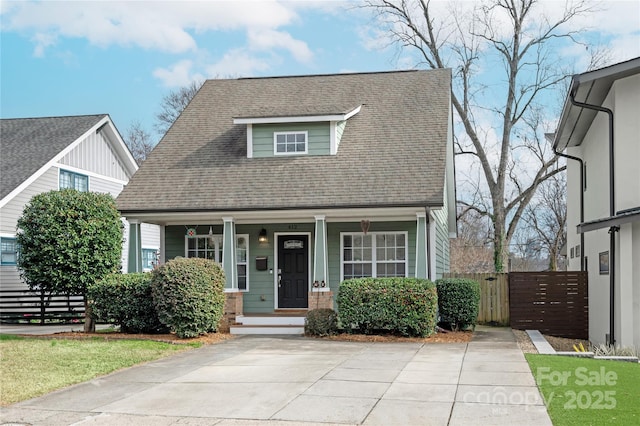 view of front of house featuring a porch, roof with shingles, and fence