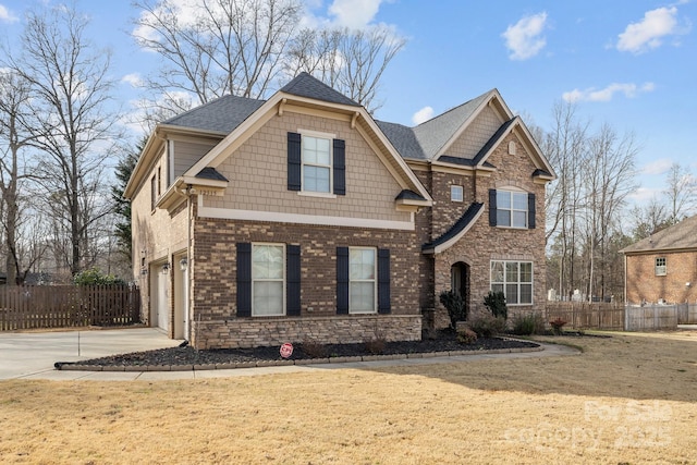 craftsman-style home featuring fence, a front lawn, concrete driveway, and brick siding