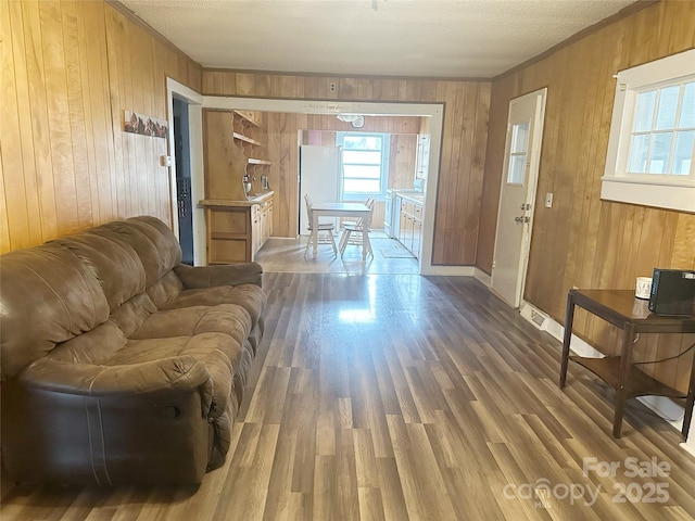 living room featuring hardwood / wood-style flooring, wooden walls, and crown molding