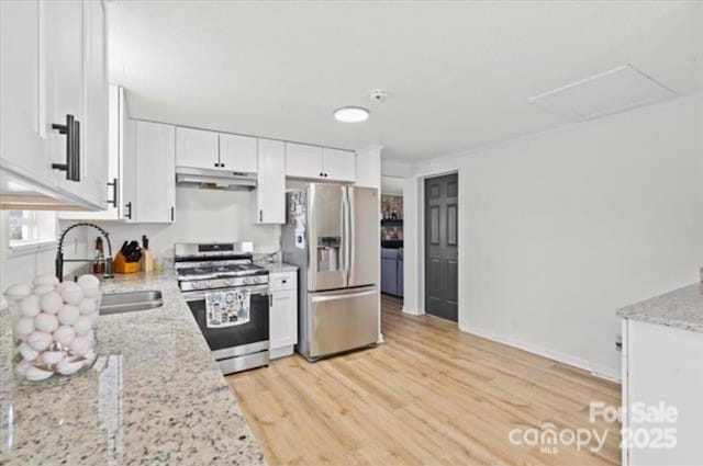 kitchen featuring white cabinetry, appliances with stainless steel finishes, light stone countertops, and light wood-type flooring