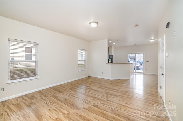 spare room with a wealth of natural light, baseboards, and light wood finished floors