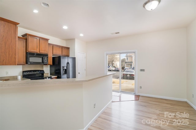 kitchen with light wood-style flooring, visible vents, light countertops, black appliances, and brown cabinetry