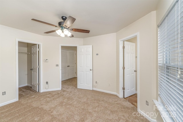 unfurnished bedroom featuring a walk in closet, light colored carpet, and baseboards