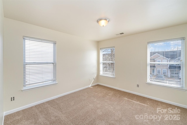 spare room featuring light carpet, visible vents, and baseboards