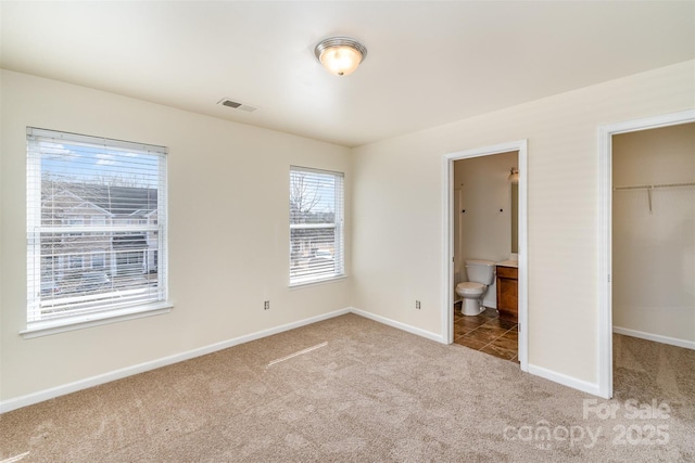 unfurnished bedroom with light carpet, visible vents, baseboards, a spacious closet, and a closet