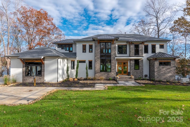prairie-style house featuring stone siding, french doors, a front yard, stucco siding, and a standing seam roof