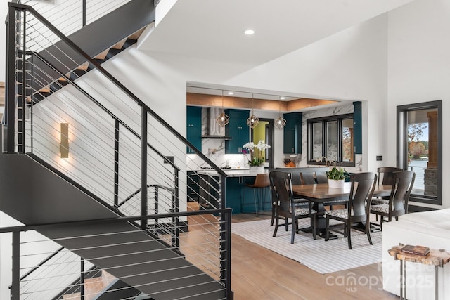 stairway featuring recessed lighting, wood finished floors, and a towering ceiling