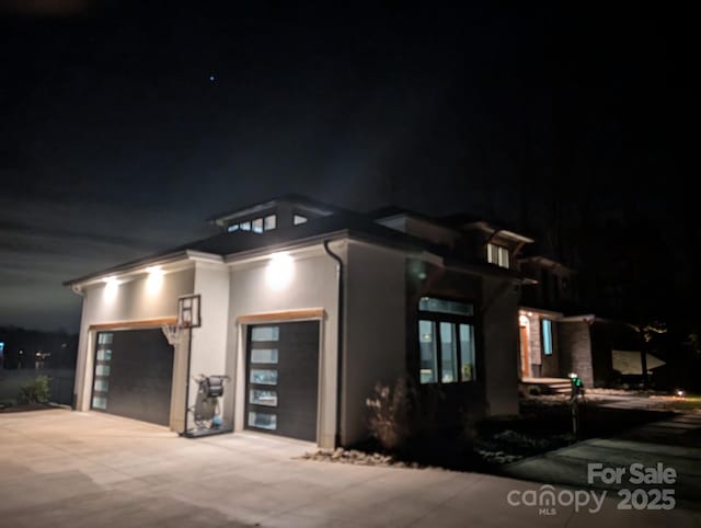 property exterior at twilight featuring a garage, concrete driveway, and stucco siding
