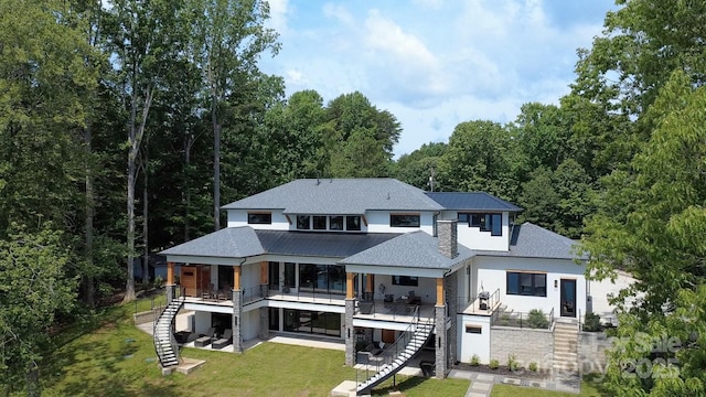 180 Willow Point Rd, Troutman, NC 28166 - back of house with stairs, a lawn, a shingled roof, stone siding, and a view of trees