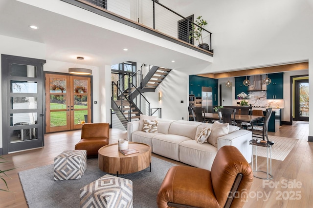 180 Willow Point Rd, Troutman, NC 28166 - living room with stairway, french doors, light wood-type flooring, a towering ceiling, and recessed lighting