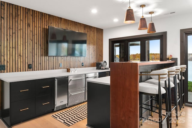 180 Willow Point Rd, Troutman, NC 28166 - kitchen featuring dark cabinetry, light countertops, light wood-type flooring, hanging light fixtures, and a kitchen breakfast bar