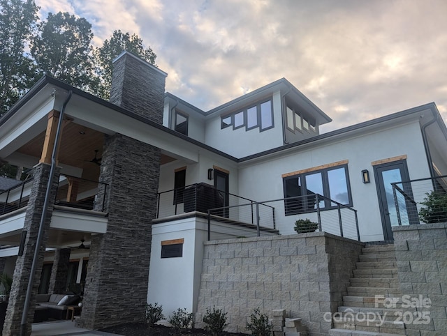 180 Willow Point Rd, Troutman, NC 28166 - view of home's exterior featuring stucco siding, stairs, a balcony, a chimney, and stone siding