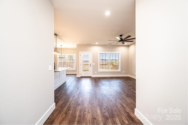 unfurnished living room with dark hardwood / wood-style flooring and ceiling fan with notable chandelier