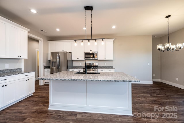 kitchen with a kitchen island with sink, pendant lighting, stainless steel appliances, and white cabinets