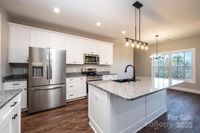 kitchen with dark wood-type flooring, sink, appliances with stainless steel finishes, an island with sink, and white cabinets