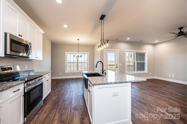 kitchen with appliances with stainless steel finishes, dark hardwood / wood-style floors, pendant lighting, an island with sink, and white cabinets