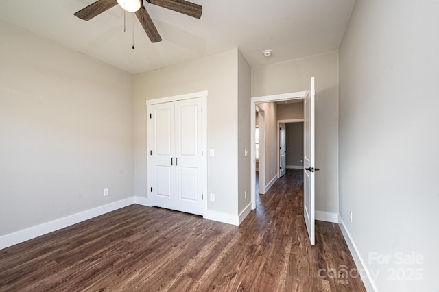 unfurnished bedroom with dark hardwood / wood-style flooring, a closet, and ceiling fan