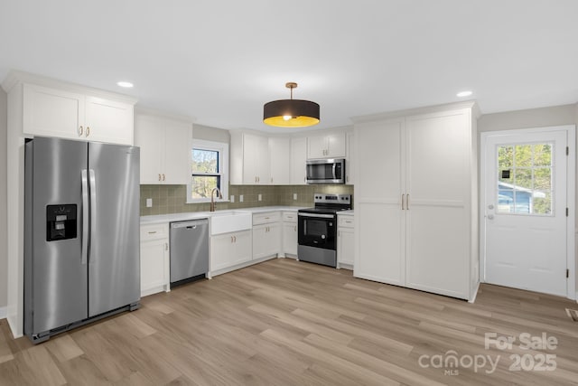 kitchen featuring appliances with stainless steel finishes, decorative light fixtures, white cabinetry, sink, and decorative backsplash