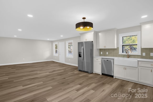 kitchen featuring stainless steel appliances, white cabinetry, sink, and tasteful backsplash