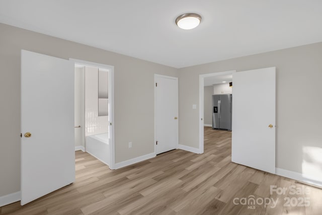 unfurnished bedroom featuring stainless steel fridge with ice dispenser and light hardwood / wood-style floors