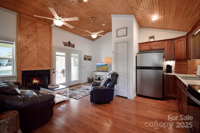 living room with sink, wood ceiling, high vaulted ceiling, a large fireplace, and light hardwood / wood-style floors