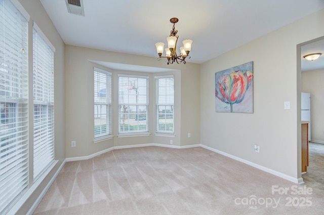 carpeted empty room featuring a chandelier