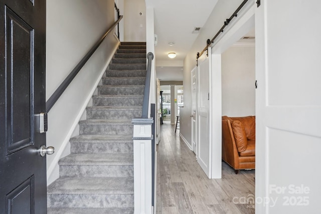 stairway featuring a barn door and hardwood / wood-style floors