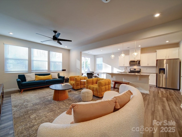 living room with sink, ceiling fan, and light hardwood / wood-style flooring