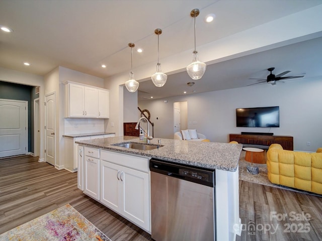 kitchen featuring sink, white cabinetry, a kitchen island with sink, hanging light fixtures, and stainless steel dishwasher