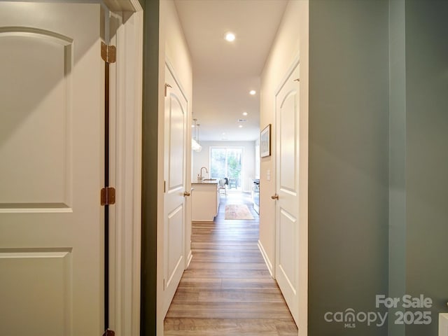 corridor featuring sink and light hardwood / wood-style floors