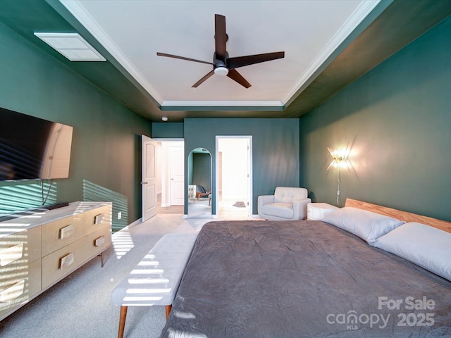 carpeted bedroom with crown molding, ceiling fan, and a tray ceiling